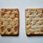 Immagine di diverse confezioni di crackers con etichette che evidenziano ingredienti poco salutari.